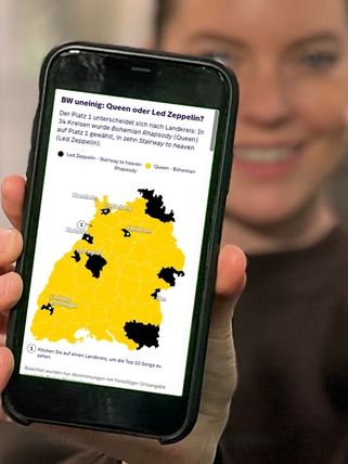 Cora Klausnitzer zeigt mit dem Finger auf die Statistik der SWR1 BW Hitparade 2025 auf ihrem Smartphone