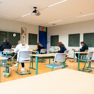 Schülerinnen und Schüler sitzen während der schriftlichen Abiturprüfung in Biologie in einem Klassenzimmer.