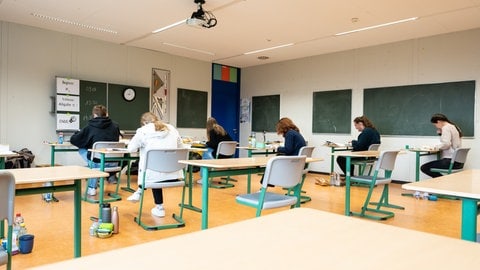 Schülerinnen und Schüler sitzen während der schriftlichen Abiturprüfung in Biologie in einem Klassenzimmer.
