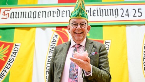 Denis Scheck, Literaturkritiker, hält vor der Verleihung des 32. Pfälzer "Saumagen-Ordens" den Preis in den Händen. Der Orden aus Rosenquarz wird jährlich von der Karneval- und Tanzsport-Gesellschaft "Schlotte" verliehen.