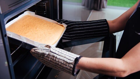 Frau holt Brot aus dem Ofen
