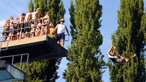 Ein junger Mann springt vom 10-Meter-Sprungturm in ein Becken.
