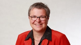 Brigitte Schäfer, Schulleiterin für Familienpflege, lächelt strahlend in die Kamera.  Sie ist die Leiterin der Berufsfachschule für Familienpflege Korntal. Dort werden Frauen und Männer zu Pflegefachkräften oder Aushilfs-Müttern und -Vätern ausgebildet. In SWR1 Leute erzählt sie, wie wichtig und vielschichtig die Arbeit der Familienpflegekräfte ist, um den Lebensalltag aufrechtzuhalten in Familien, die kurzzeitig ohne Hilfe nicht mehr auskommen.