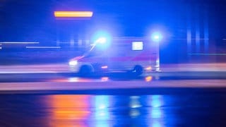 Ein Krankenwagen fährt im Dunkeln mit Blaulicht auf einer Straße. Bei Frankenthal ist ein Autofahrer nach einem Überholmanöver gestorben.