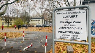 Schilder weisen auf die "Kiss and Go-Zone" an der Westend Grundschule in Worms hin. Dort können Kinder sicher aus den Autos ihrer Eltern aussteigen