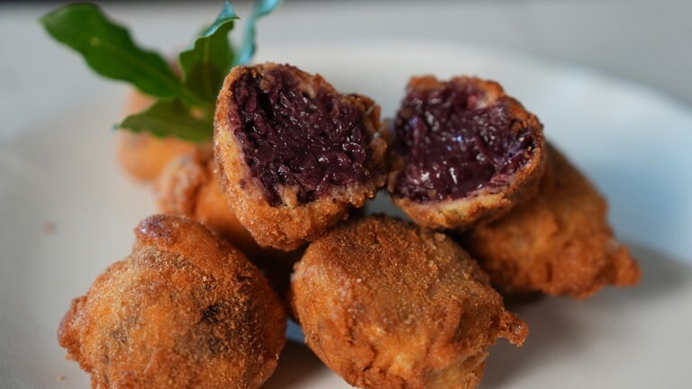 Gebackene Rotkohl-Knödel, die außen kross und innen saftig sind, angerichtet auf einem weißen Teller.