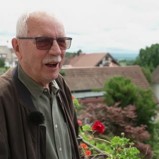 Wolfram Kindl steht auf seinem balkon und grinst.