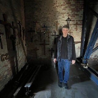 Kreuze hängen an einer alten Wand in einem Kirchturm: In der Georgskirche bekommen alte Kreuze und Kruzifixe eine neue Heimat