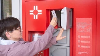 Eine Kundin entnimmt ihre Bestellung aus dem Ausgabe-Automaten vor der Kreuzberg-Apotheke in Cochem.