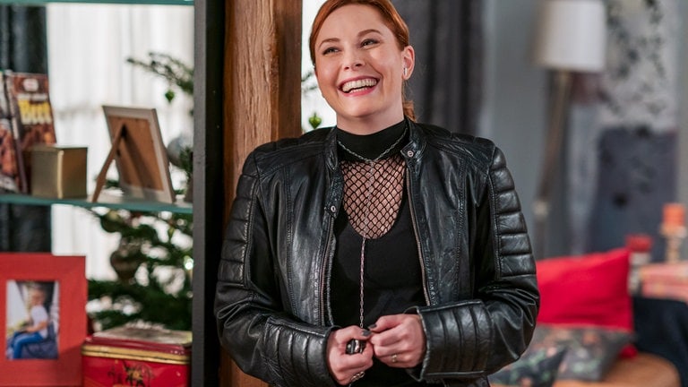 Lissy (Elinor Eidt) steht lachend in Andreas' Wohnung