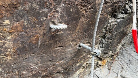 Beim Klettersteig Neuerburg gibt es verschiedene Arten von Tritten, wie diesen hier. Daneben ist das Seil, die "Lifeline", gespannt, an dem Kletterer ihre Sicherungsseile mit Karabinern einhaken.
