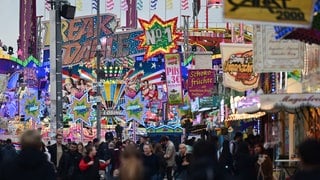 Bunte Reklametafeln leuchten auf dem Gelände des Volksfests Cannstatter Wasen.