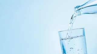 Wasser fließt in ein Glas- Wegen der großen Hitze rufen Kommunen zum Wassersparen auf