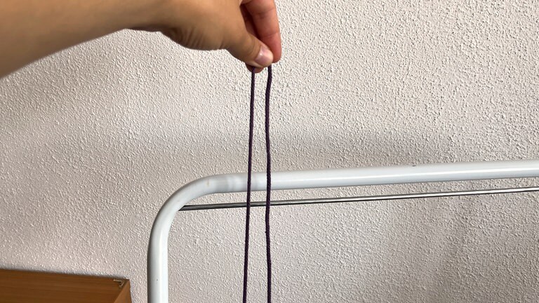 Das Garn wird nun unter Spannung doppelt nach oben geführt, sodass eine Schlaufe entsteht.