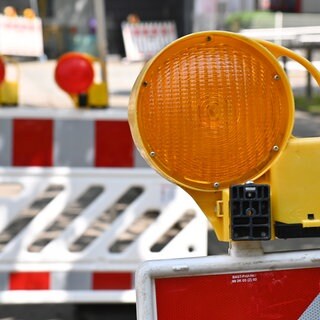 Eine orangene Warnleuchte auf einem rot-weißen Absperrzaun. Zwei Brücken in Speyer müssen wegen Brückenschäden vom Landesbetrieb für Mobilität gesperrt werden. Das wird für Probleme im Stadtverkehr sorgen.