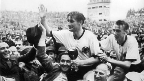 Die deutschen Fußballspieler Fritz Walter (mit dem Pokal in den Händen) und Horst Eckel werden am 4. Juli 1954 von Fans frenetisch gefeiert und auf den Schultern durch das Stadion getragen. Mit einem 3:2--Sieg über Ungarn im Endspiel der Fußball-Weltmeisterschaft 1954 in BernSchweiz gewann Deutschland den Titel.
