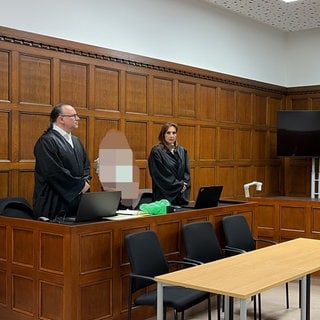 Der Angeklagte mit seinen Anwältebn vor Gericht: Der Mann soll bei einer Geiselnahme ein Baby verletzt haben