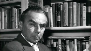 Erich Kästner 1959 vor einem Bücherregal