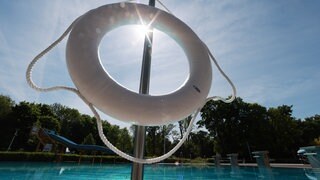 Ein Rettungsring hängt in der Sonne in einem Freibad. (Symbolbild) Bei einem Badeunfall in einem Erlebnisbad in Albstadt (Zollernalbkreis) war ein Mädchen ertrunken.