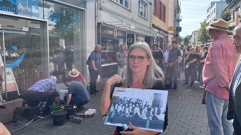 Ein eherenamtliches Mitglied der Stolperstein-Initiative zeigt ein Foto der jüdischen Sonderklasse in der Röhmschule 1938. Auf diesem sind mehrere Kinder mit Namen markiert. 