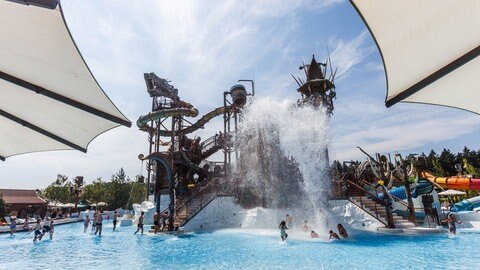 Wasser fällt aus einer Attraktion auf Menschen, die im Wasserpark Rulantica baden.