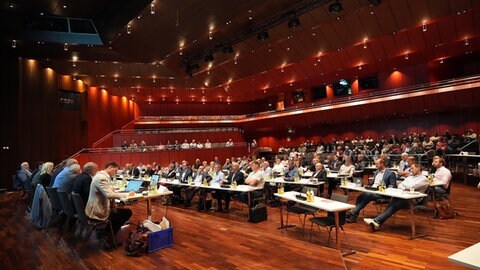 Die Kreisräte des Zollernalbkreises sitzen an Tischen in der Balinger Stadthalle. 