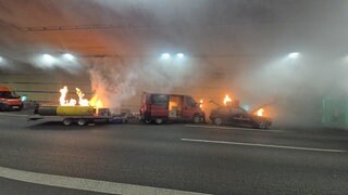 Ein Auto, ein Transporter und ein Anhänger stehen im Hechtsheimer Tunnel und brennen. 