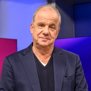 Moderator Hubertus Meyer-Burckhardt schaut direkt in die Kamera. 