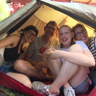 Eine Familie schaut aus einem Zelt.