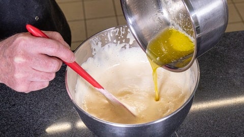 In den Teig für den Biskuit der Erbeertorte wird zuletzt die heiße Butter gerührt.