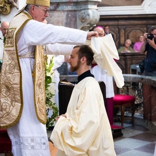 Abt Maximilian Heim (l) bekleidet bei der feierlichen Profess Frater Christoph Benedikt Seemann OCist (M) mit einer geweihten Mönchskutte. Erstmals seit fast 209 Jahren legt wieder ein Zisterziensermönch im Kloster Neuzelle die ewigen Gelübde ab.