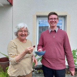 Margit und Oliver essen Kirschen und lächeln in die Kamera.