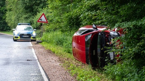 Ein rotes Auto liegt auf der Seite im Straßengraben. Eine Frau ist bei Waldalgesheim verunglückt