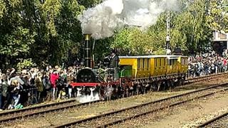 Eine Eisenbahn fährt an Zuschauern vorbei