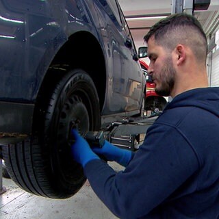 Ein Mechaniker wechselt in einer Werkstatt einen Reifen an einem Auto