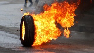 Brennender Autoreifen rollt über eine Straße (Symbolbild)