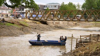 Ein THW-Mitarbeiter bringt Menschen mit einem Fährboot über die Ahr in Rheinland-Pfalz, weil die Brücke nicht mehr existiert.