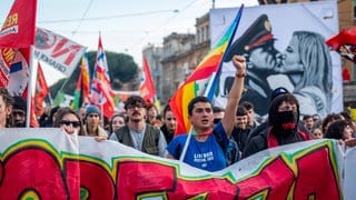 Tausende Menschen demonstrieren am 14. Dezember 2024 in Rom gegen das Gesetz 1660, das das Demonstrationsrecht einschränken soll und u.a. härtere Strafen für Demonstrationen und Straßenblockaden vorsieht. Ein Plakat der Demonstranten zeigt einen Kuss zwischen dem faschistischen "Duce" Benito Mussolini und Italiens Regierungschefin Giorgia Meloni.