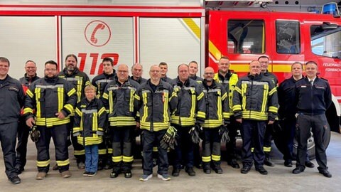 Feuerwehrleute vor einem Feuerwehrfahrzeug.