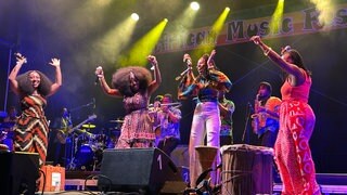 Mehrere Schwarze Sängerinnen stehen mit verschiedenen Schwarzen Musikern auf der Bühne des Music Festivals in Emmendingen.  