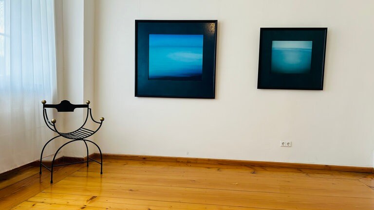 Zwei Kunstwerke hängen in einem Ausstellungsraum.  Im Schloss Isny würdigt eine Sonderausstellung den Künstler Friedrich Hechelmann.
