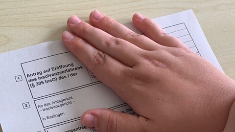 Maria (Name geändert) legt ihre Hand auf einen Insolvenzantrag.