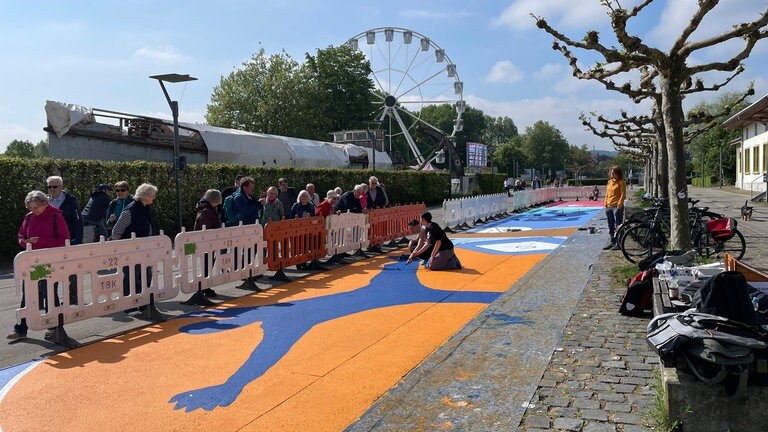Entlang des Hafens in Konstanz sind bunte Bilder aufgemalt, man sieht sportliche Motive wie Bälle.