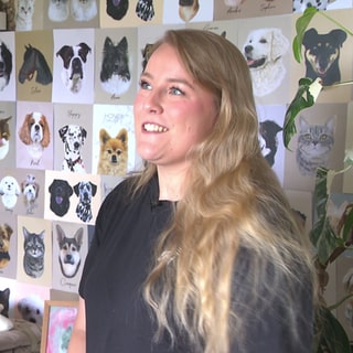 Alicia Härter steht vor ihren selbst gemalten Hundeportraits. 