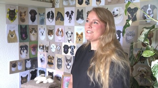 Alicia Härter steht vor ihren selbst gemalten Hundeportraits. 