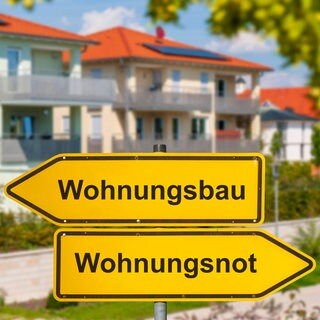 Neubauten, davor Wegweiser "Wohnungsbau": Strenge Vorschriften und Normen treiben die Baukosten in die Höhe. Pilotbauten zeigen, wie es anders geht – auch wenn dabei manche Regel gebrochen wird. Die Bundesregierung will das jetzt per Gesetz ermöglichen.