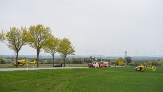 Mehrere Rettungswägen und zwei Hubschrauber stehen an einer Straße bei Albig im Kreis Alzey-Worms.
