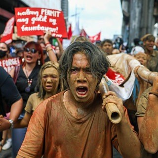Junge Leute protestieren, mit Schlamm beschmutzt, in Manila gegen Korruption im Klimaschutz: Auf den Philippinen, wo Taifune immer mehr Lebensraum armer Menschen überfluten, flossen bereits Milliarden Euro in die Taschen von Politikern und Bauunternehmen.