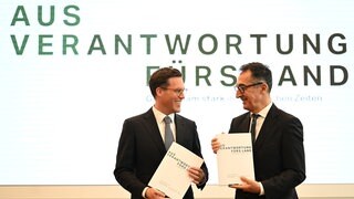 Cem Özdemir (r, Bündnis 90  Die Grünen) und Manuel Hagel (CDU) nehmen in der Sparkassenakademie Baden-Württemberg an der Präsentation des Koalitionsvertrags von Grünen und CDU teil.