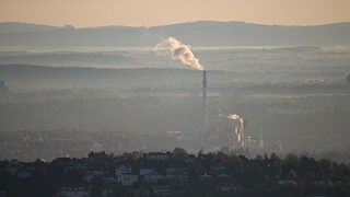 Dampf bildet im Morgendunst eine Wolke aus einem Schornstein eines Kraftwerks.